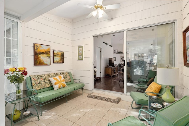 living area with tile patterned floors, ceiling fan, and beamed ceiling