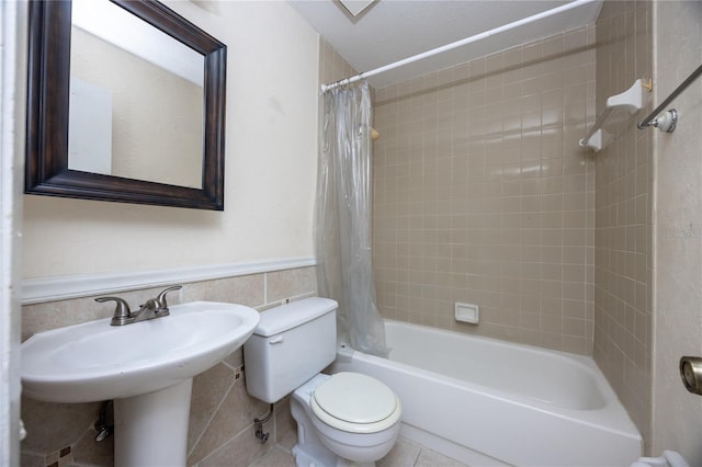 bathroom featuring toilet, shower / tub combo with curtain, and tile walls