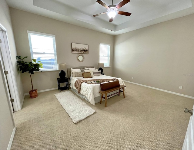 carpeted bedroom featuring a tray ceiling and ceiling fan