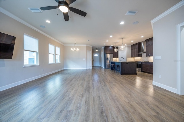 unfurnished living room with ceiling fan with notable chandelier, dark hardwood / wood-style floors, crown molding, and sink