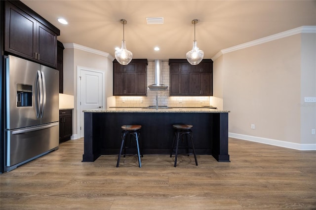 kitchen featuring stainless steel fridge with ice dispenser, decorative light fixtures, wall chimney range hood, and light hardwood / wood-style floors