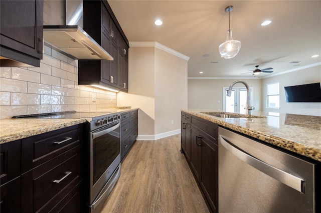 kitchen with light stone countertops, sink, wall chimney exhaust hood, stainless steel appliances, and light hardwood / wood-style flooring