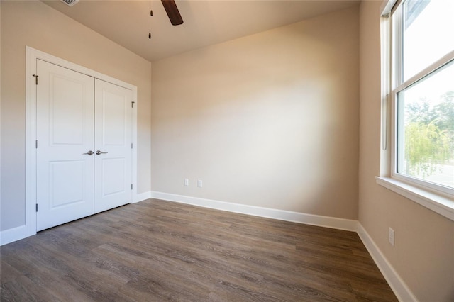 unfurnished bedroom featuring ceiling fan, dark hardwood / wood-style flooring, and a closet