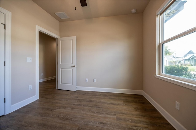 unfurnished bedroom with ceiling fan, dark wood-type flooring, and multiple windows