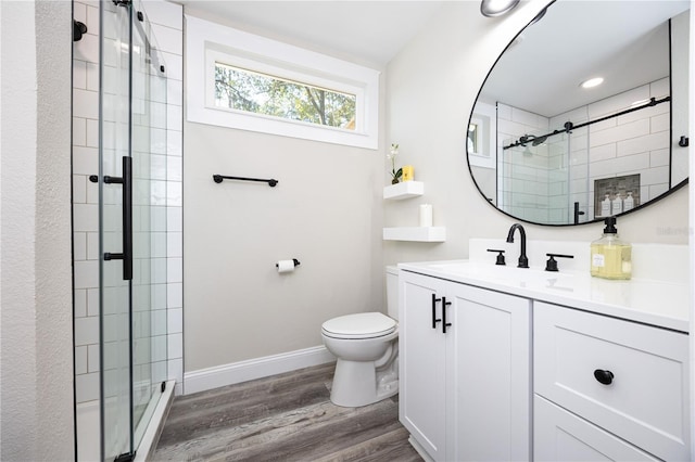 bathroom with wood-type flooring, vanity, toilet, and a shower with shower door