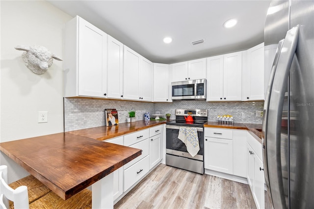 kitchen featuring stainless steel appliances, white cabinetry, light hardwood / wood-style flooring, and wooden counters