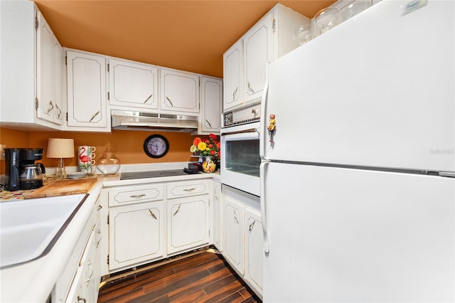 kitchen with white cabinets, dark hardwood / wood-style flooring, and white appliances