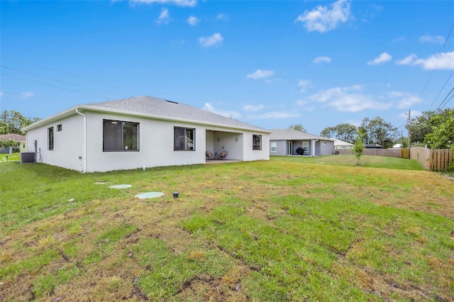 back of house featuring central AC unit and a lawn