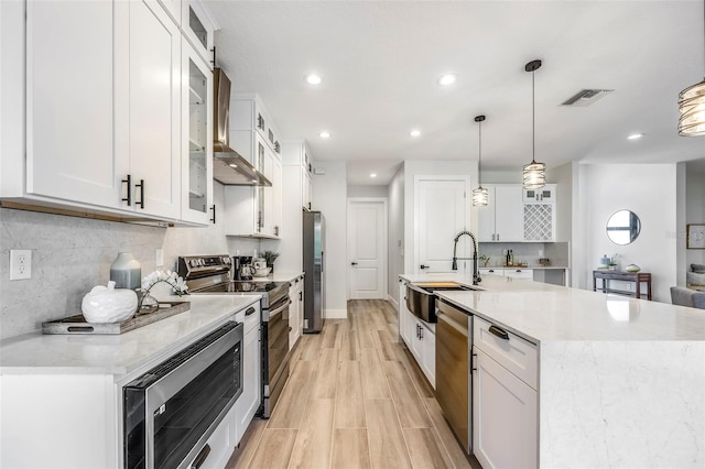 kitchen with appliances with stainless steel finishes, white cabinetry, and hanging light fixtures