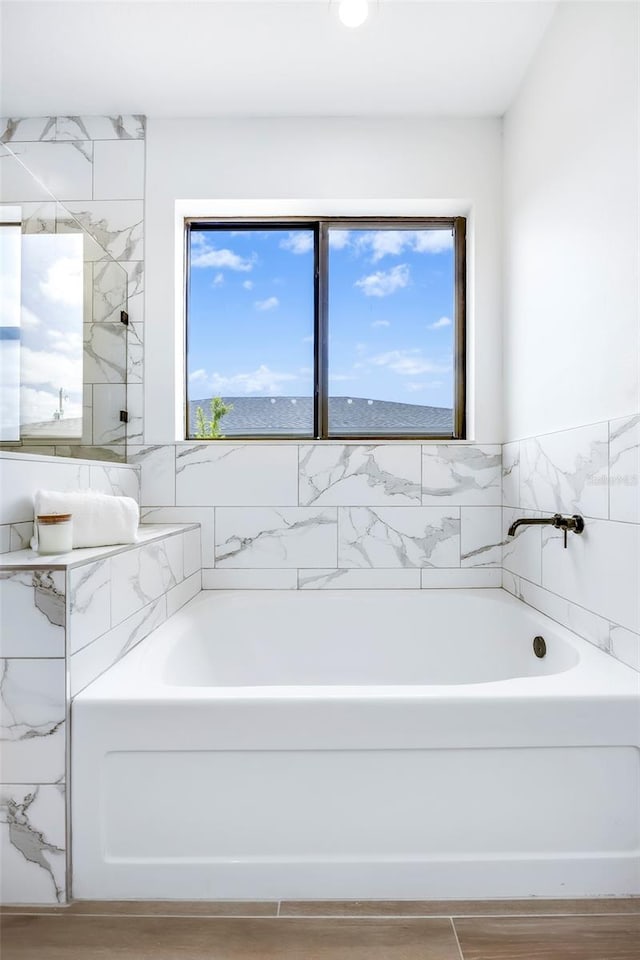 bathroom featuring hardwood / wood-style floors, a tub to relax in, and a healthy amount of sunlight