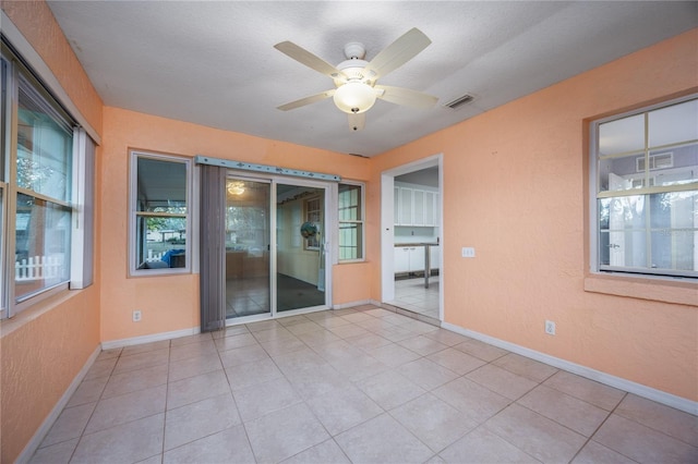 interior space featuring ceiling fan, light tile patterned floors, and a textured ceiling