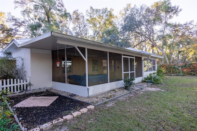 view of side of home with a sunroom and a lawn