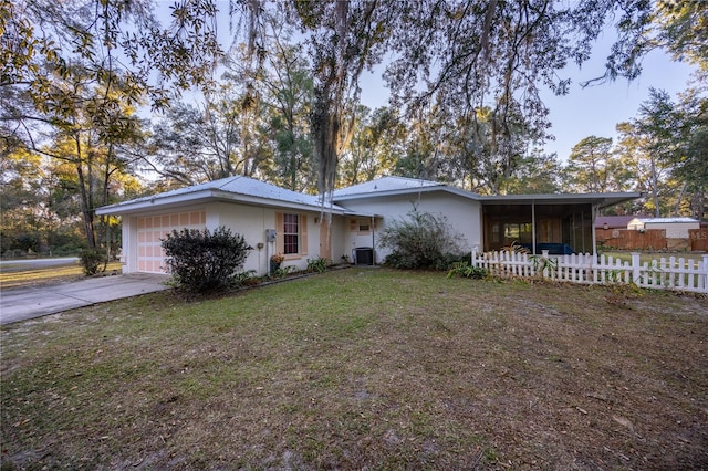 ranch-style house featuring a front yard, a garage, and central AC unit