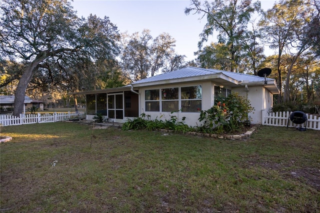 rear view of property featuring a sunroom and a yard