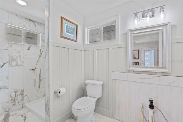 bathroom with a tile shower and toilet