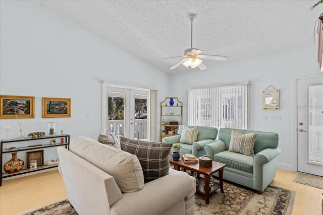 living room with french doors, a textured ceiling, ceiling fan, high vaulted ceiling, and light hardwood / wood-style flooring