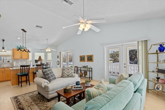 living room featuring french doors, vaulted ceiling, ceiling fan, a textured ceiling, and light hardwood / wood-style floors