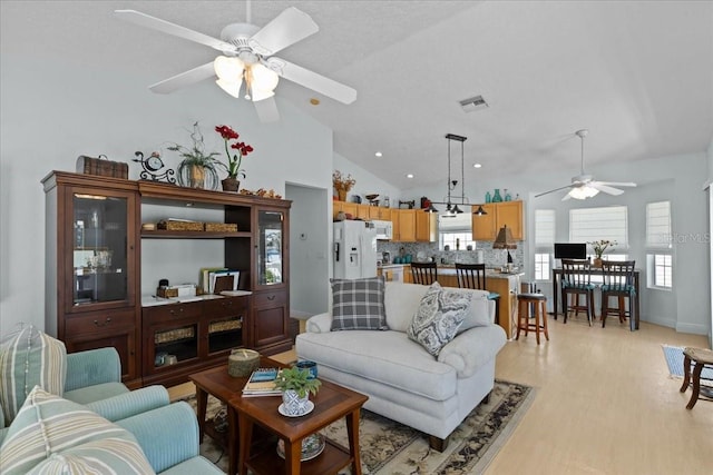 living room with ceiling fan, light hardwood / wood-style floors, and high vaulted ceiling