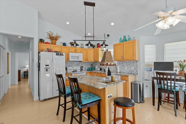 kitchen featuring white appliances, tasteful backsplash, light hardwood / wood-style flooring, and a kitchen island with sink