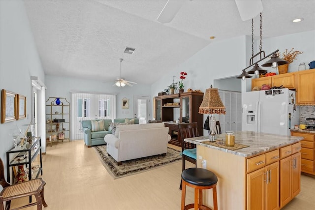 kitchen with ceiling fan, white fridge with ice dispenser, light hardwood / wood-style floors, vaulted ceiling, and a kitchen island