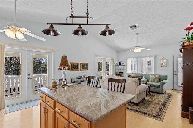 kitchen featuring a textured ceiling, french doors, vaulted ceiling, and light hardwood / wood-style flooring