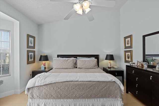 bedroom with ceiling fan, light hardwood / wood-style flooring, and a textured ceiling