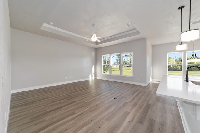 1069 NW 132nd Blvd, Newberry, FL 32669 - unfurnished living room with a raised ceiling, a ceiling fan, light wood finished floors, and baseboards