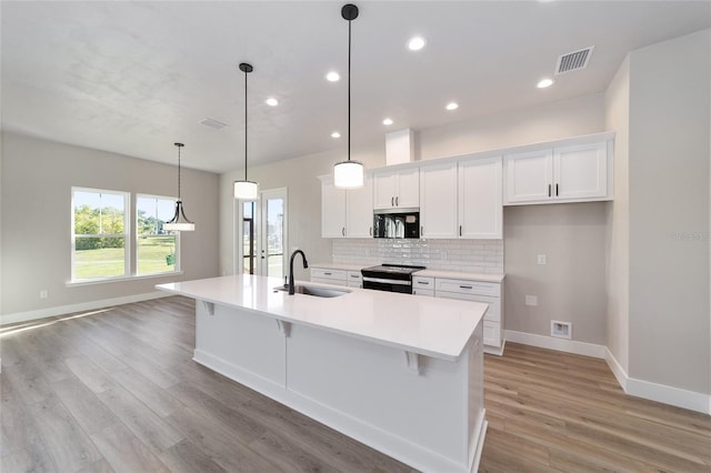 kitchen with pendant lighting, sink, light hardwood / wood-style flooring, black range with electric cooktop, and a large island