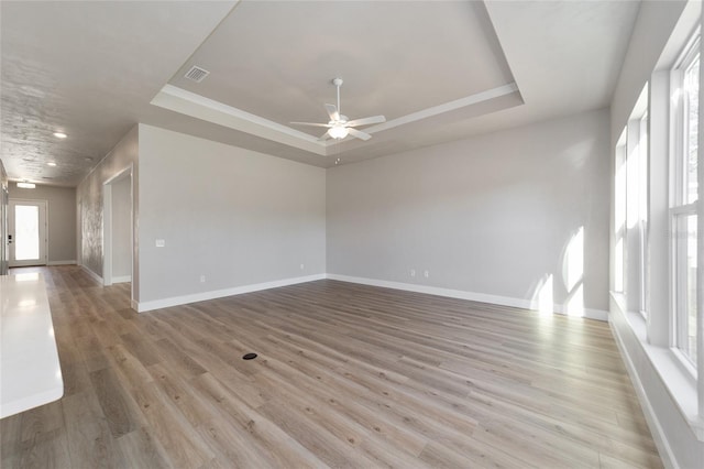 empty room featuring light hardwood / wood-style floors, a raised ceiling, and ceiling fan