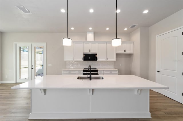 kitchen featuring a spacious island, sink, white cabinets, and pendant lighting