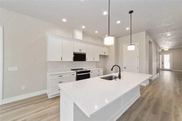 1069 NW 132nd Blvd, Newberry, FL 32669 - kitchen featuring a sink, electric range, a large island with sink, white cabinetry, and light wood-style flooring