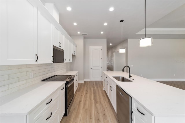 kitchen featuring pendant lighting, a kitchen island with sink, sink, appliances with stainless steel finishes, and white cabinetry