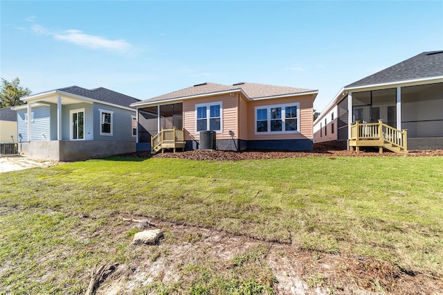 back of house featuring a sunroom, central air condition unit, and a lawn