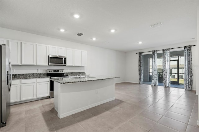 kitchen with a kitchen island with sink, sink, stone countertops, white cabinetry, and stainless steel appliances