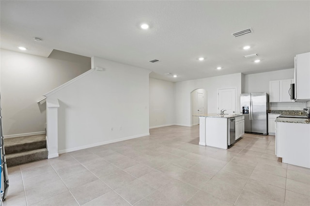 kitchen with white cabinetry, sink, light stone counters, a center island with sink, and appliances with stainless steel finishes