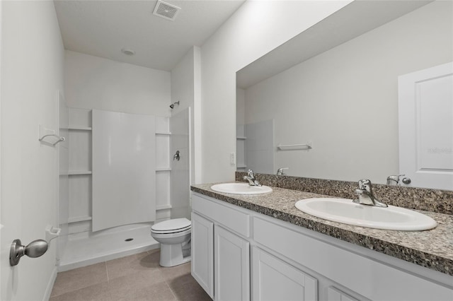 bathroom featuring a shower, vanity, tile patterned floors, and toilet