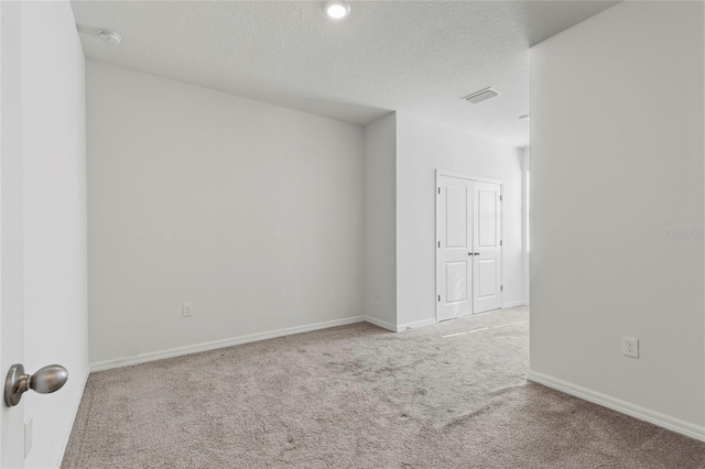 empty room featuring light carpet and a textured ceiling