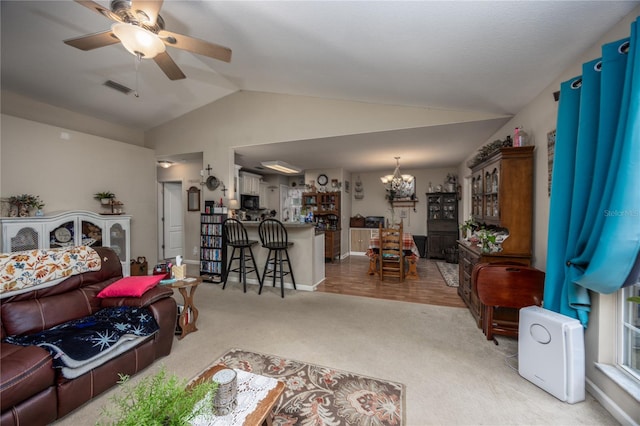 carpeted living room with ceiling fan with notable chandelier and lofted ceiling