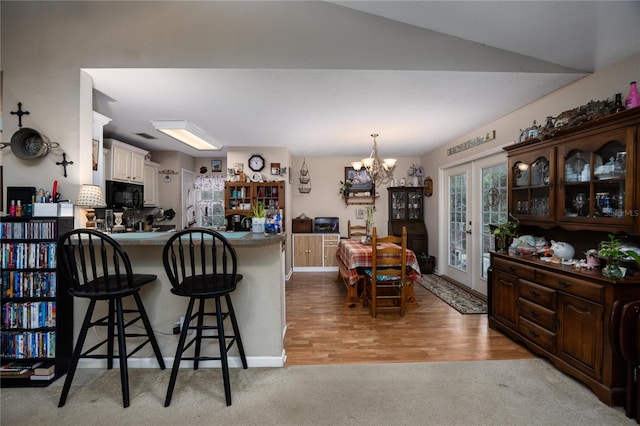 kitchen featuring a breakfast bar, lofted ceiling, french doors, light hardwood / wood-style floors, and kitchen peninsula