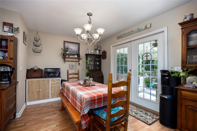 dining room with a chandelier, french doors, and light wood-type flooring