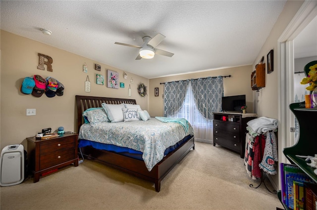 bedroom featuring ceiling fan, light carpet, and a textured ceiling