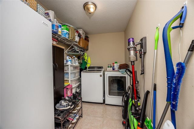 clothes washing area featuring washer and clothes dryer, light tile patterned floors, and a textured ceiling