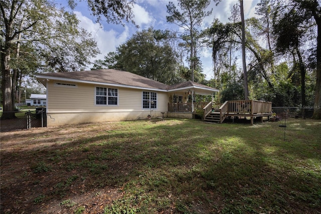 rear view of house featuring a yard and a wooden deck