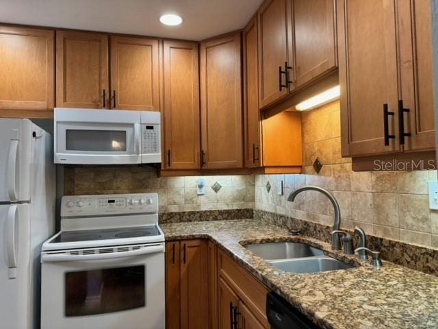 kitchen featuring white appliances, sink, stone counters, and tasteful backsplash