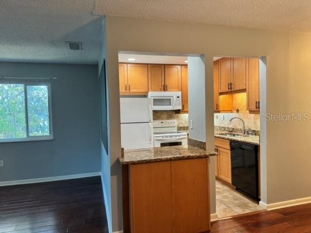 kitchen with a textured ceiling, white appliances, light hardwood / wood-style floors, and sink