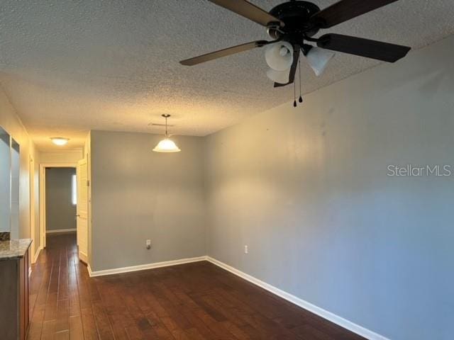 empty room featuring a textured ceiling, ceiling fan, and dark wood-type flooring