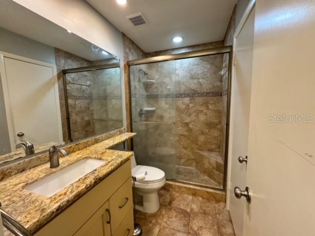 bathroom featuring vanity, a shower with shower door, and toilet