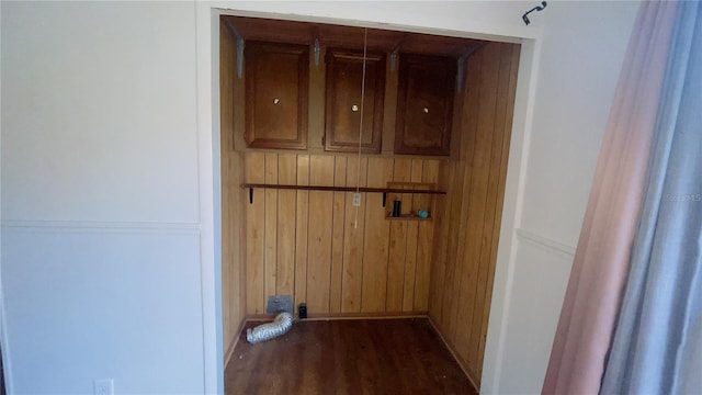 laundry area featuring wood walls and dark wood-type flooring