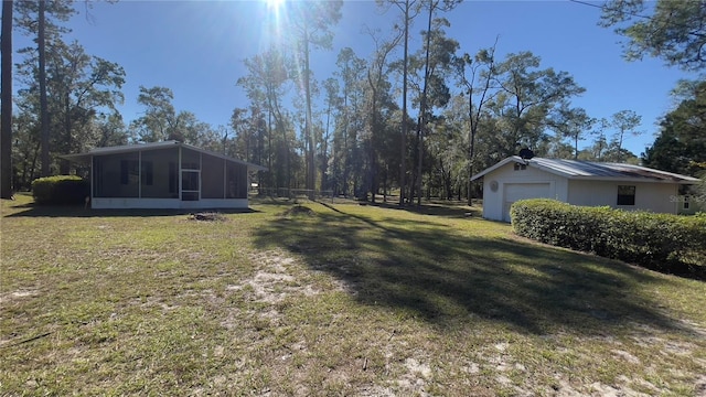 view of yard with a sunroom, a garage, and an outbuilding