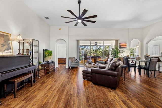 living room with ceiling fan, a towering ceiling, and dark hardwood / wood-style floors